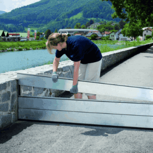 Frau installiert eine Wasserbarriere, um das Haus vor Hochwasser zu schützen.